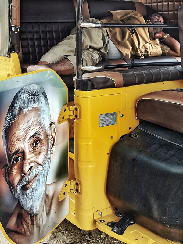 Auto ricksha adorned with a stylised sticker image of Bhagavan Sri Ramana Maharshi, while the driver rests inside